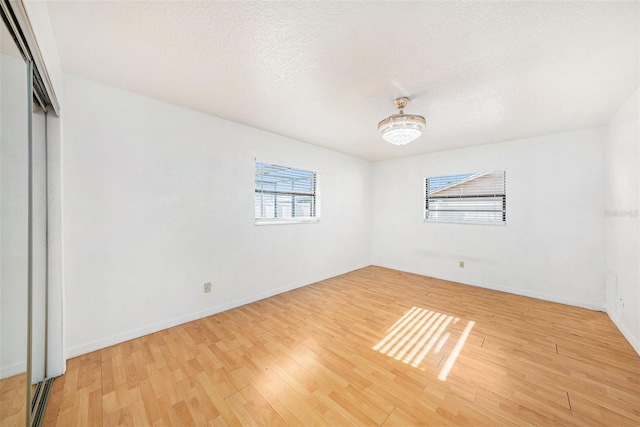 8744 Andros Ln, Port Richey, FL 34668 - unfurnished bedroom featuring light wood-style flooring, a closet, baseboards, and a textured ceiling
