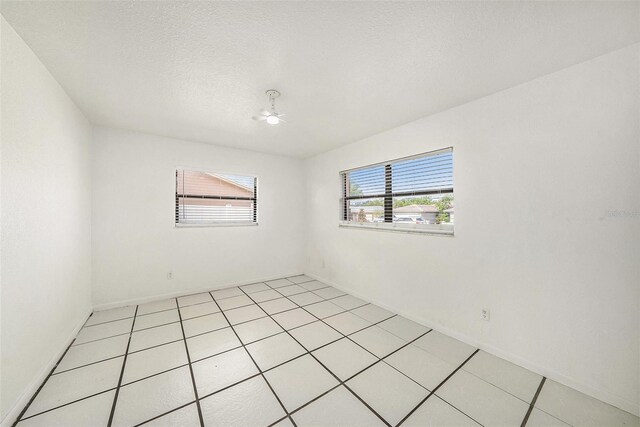 8744 Andros Ln, Port Richey, FL 34668 - spare room with baseboards, light tile patterned flooring, and a ceiling fan