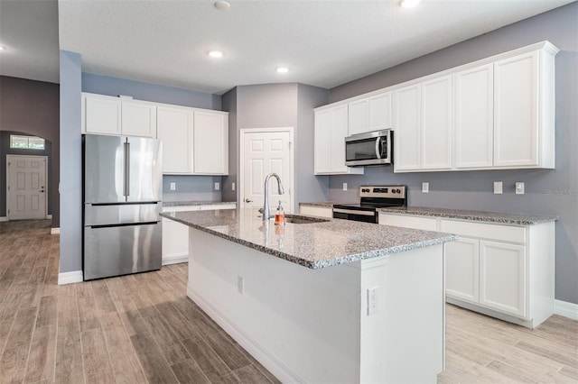 12420 Brick Cobblestone Dr, Riverview, FL 33579 - kitchen featuring appliances with stainless steel finishes, a sink, a kitchen island with sink, light wood-style floors, and baseboards