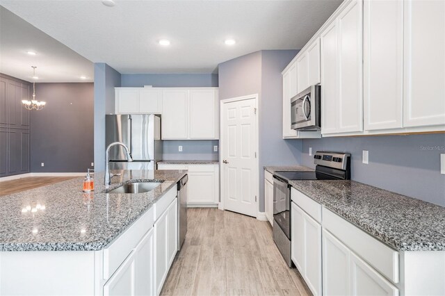 12420 Brick Cobblestone Dr, Riverview, FL 33579 - kitchen with stainless steel appliances, a sink, light wood-type flooring, a kitchen island with sink, and recessed lighting