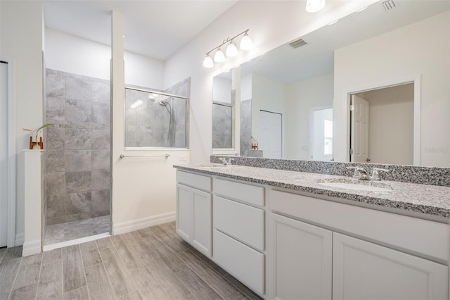 12420 Brick Cobblestone Dr, Riverview, FL 33579 - bathroom featuring walk in shower, wood finished floors, double vanity, and baseboards