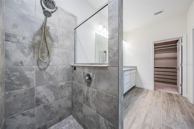 12420 Brick Cobblestone Dr, Riverview, FL 33579 - bathroom with a tile shower, wood finished floors, vanity, a walk in closet, and baseboards