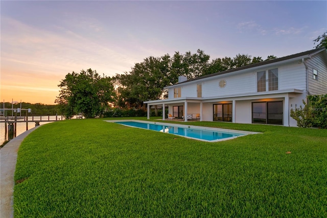 218 Colony Point Rd S, Saint Petersburg, FL 33705 - back of property at dusk with an outdoor pool, a lawn, a chimney, and a patio