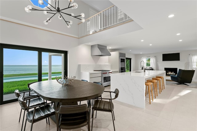 218 Colony Point Rd S, Saint Petersburg, FL 33705 - dining space with a water view, a lit fireplace, a chandelier, recessed lighting, and a towering ceiling