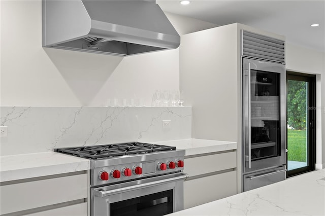 218 Colony Point Rd S, Saint Petersburg, FL 33705 - kitchen featuring wall chimney exhaust hood, high end stainless steel range, decorative backsplash, recessed lighting, and light stone counters