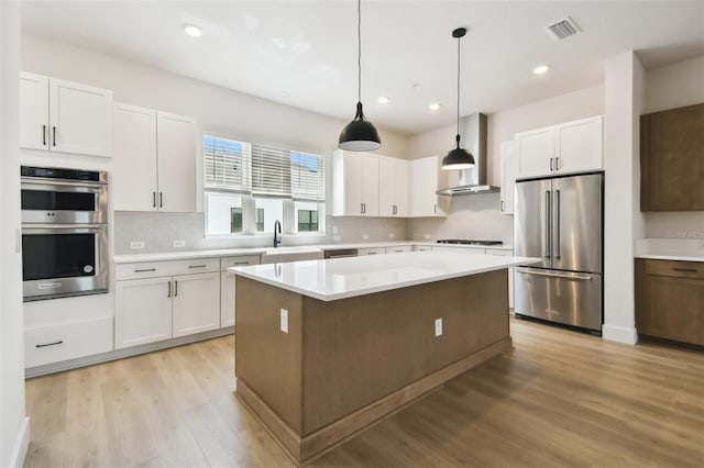 7240 Sutton Ln, Sarasota, FL 34240 - kitchen with stainless steel appliances, wall chimney exhaust hood, light wood finished floors, tasteful backsplash, and white cabinets