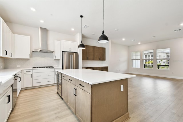 7240 Sutton Ln, Sarasota, FL 34240 - kitchen featuring wall chimney range hood, stainless steel appliances, a kitchen island, backsplash, and light wood-style flooring