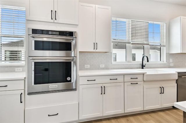 7240 Sutton Ln, Sarasota, FL 34240 - kitchen with appliances with stainless steel finishes, a sink, white cabinetry, backsplash, and light countertops