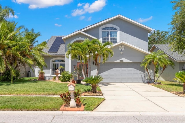 view of front of home with a front yard, driveway, solar panels, stucco siding, and an attached garage