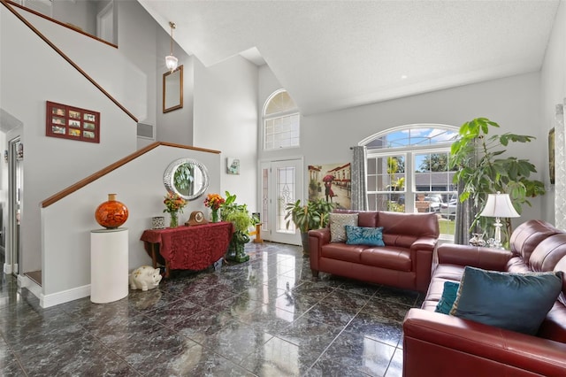 living area featuring baseboards, a high ceiling, and stairway