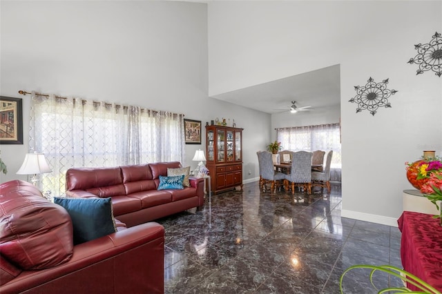 living room featuring a towering ceiling, baseboards, a ceiling fan, and marble tiled flooring