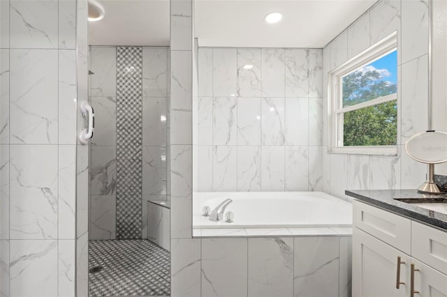 full bath with a garden tub, tiled shower, vanity, and tile walls
