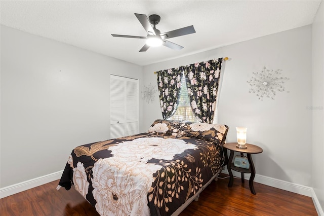 bedroom with baseboards, wood finished floors, a closet, and a ceiling fan