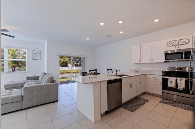 6542 95th Pl N, Pinellas Park, FL 33782 - kitchen featuring appliances with stainless steel finishes, open floor plan, a sink, a peninsula, and white cabinetry