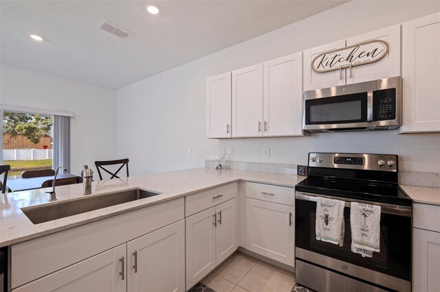 6542 95th Pl N, Pinellas Park, FL 33782 - kitchen with appliances with stainless steel finishes, a sink, white cabinetry, light stone counters, and light tile patterned floors