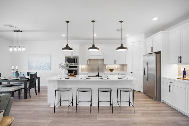 16117 Rosemallow Ln, Alva, FL 33920 - kitchen featuring appliances with stainless steel finishes, tasteful backsplash, white cabinets, light countertops, and a breakfast bar area