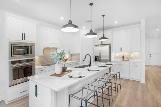 16117 Rosemallow Ln, Alva, FL 33920 - kitchen featuring stainless steel appliances, a sink, tasteful backsplash, light wood-style flooring, and white cabinets