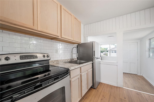 1527 E Lake Ave, Tampa, FL 33610 - kitchen featuring appliances with stainless steel finishes, light brown cabinetry, a sink, light wood finished floors, and decorative backsplash