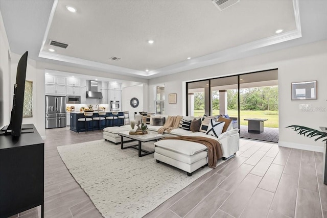 33750 Ocean Spray Ln, Wesley Chapel, FL 33543 - living room with a tray ceiling, wood finish floors, recessed lighting, baseboards, and ornamental molding