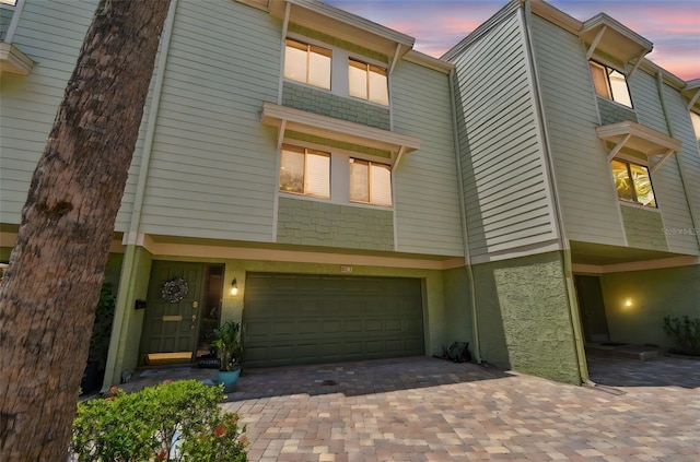 multi unit property featuring a garage and decorative driveway