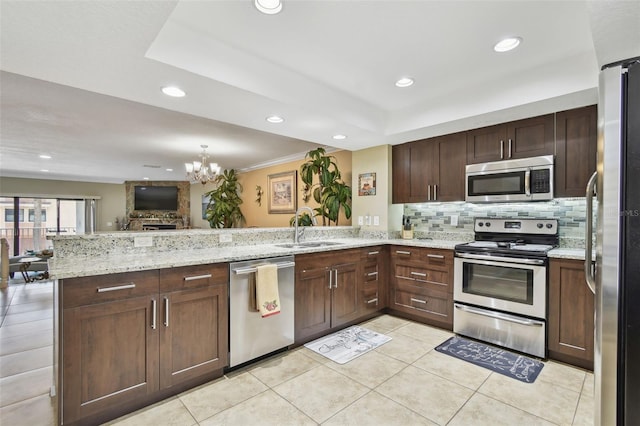 kitchen featuring stainless steel appliances, a sink, a chandelier, tasteful backsplash, and light tile patterned floors