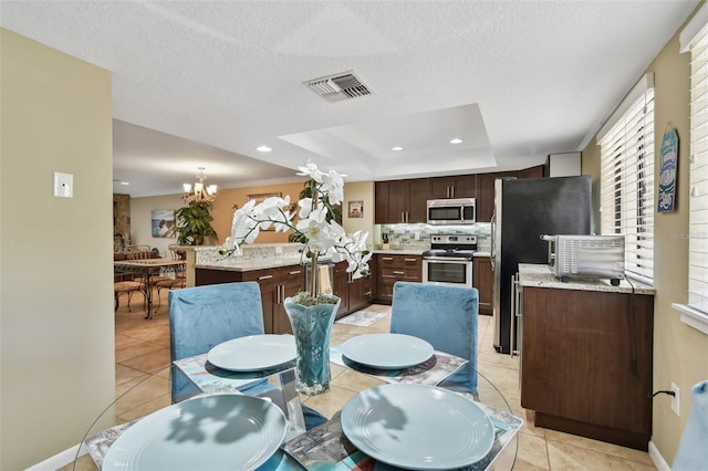 dining space with a tray ceiling, a chandelier, light tile patterned floors, and recessed lighting