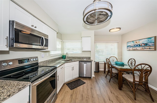 6151 Bahia Del Mar Blvd Unit 126, Saint Petersburg, FL 33715 - kitchen with stainless steel appliances, a sink, light wood finished floors, white cabinetry, and baseboards