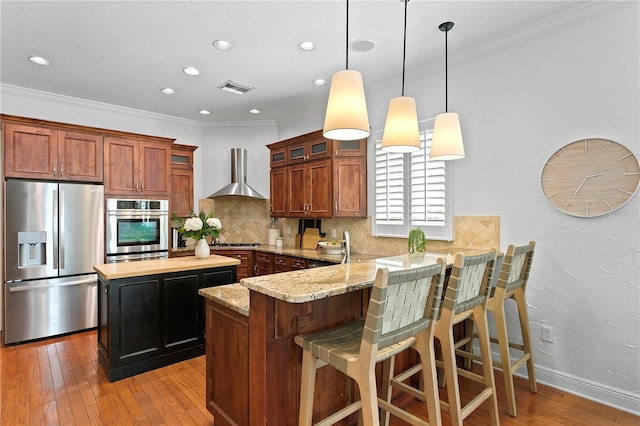 2936 W Knights Ave Unit A, Tampa, FL 33611 - kitchen with stainless steel appliances, wall chimney range hood, hardwood / wood-style flooring, tasteful backsplash, and recessed lighting