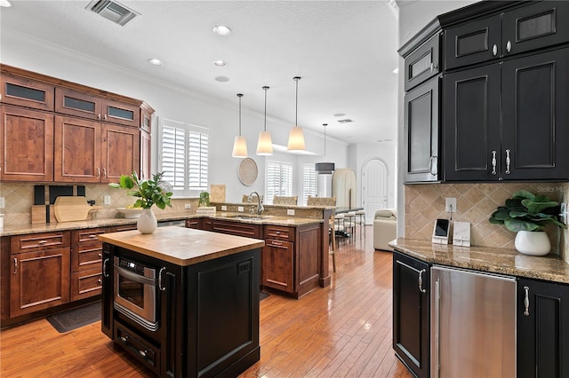 2936 W Knights Ave Unit A, Tampa, FL 33611 - kitchen with a sink, a peninsula, wooden counters, ornamental molding, and fridge