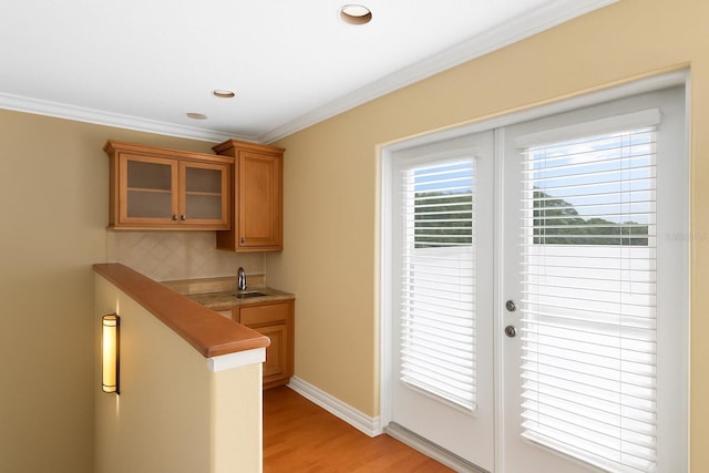 2936 W Knights Ave Unit A, Tampa, FL 33611 - kitchen featuring a sink, glass insert cabinets, crown molding, light wood finished floors, and tasteful backsplash