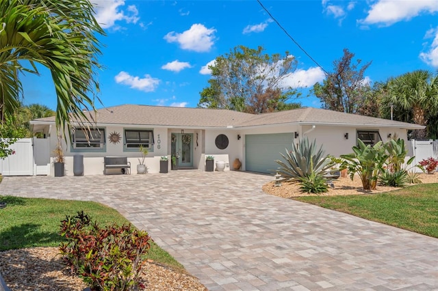 106 Midway Is, Clearwater Beach, FL 33767 - single story home featuring an attached garage, stucco siding, driveway, and a gate