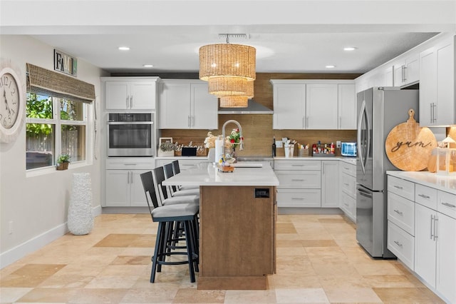 106 Midway Is, Clearwater Beach, FL 33767 - kitchen featuring appliances with stainless steel finishes, tasteful backsplash, a center island, light countertops, and a kitchen breakfast bar