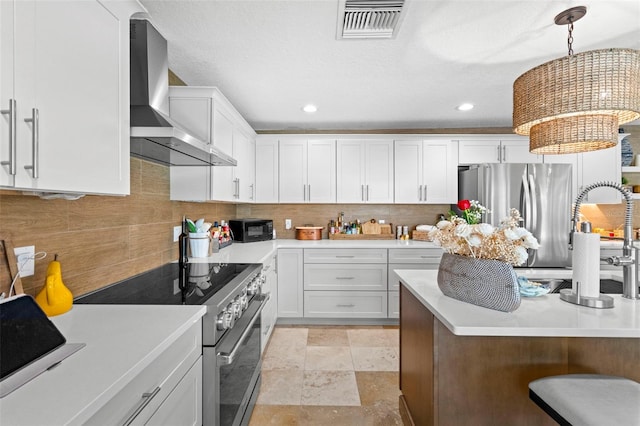106 Midway Is, Clearwater Beach, FL 33767 - kitchen featuring wall chimney range hood, appliances with stainless steel finishes, light countertops, tasteful backsplash, and recessed lighting