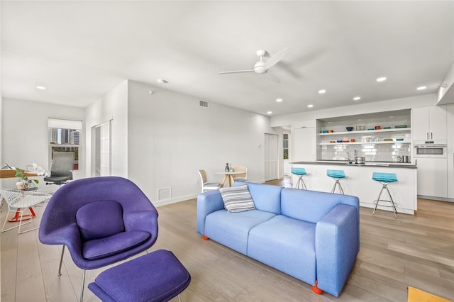 living room with a ceiling fan, light wood-type flooring, recessed lighting, and baseboards