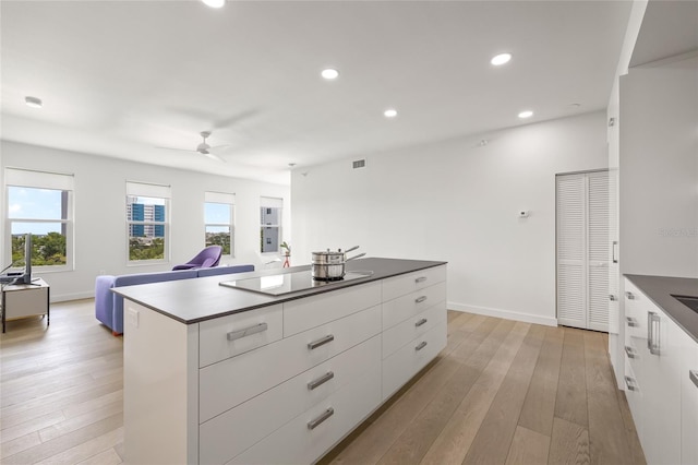 kitchen with modern cabinets, black electric cooktop, white cabinets, a ceiling fan, and healthy amount of natural light