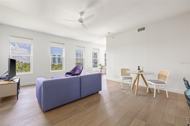 living room featuring a ceiling fan, hardwood / wood-style flooring, and baseboards