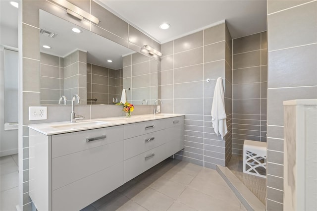 full bath with tile walls, tile patterned flooring, and double vanity