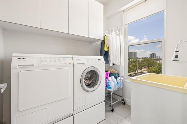 laundry area with cabinet space, washing machine and clothes dryer, light tile patterned floors, and baseboards