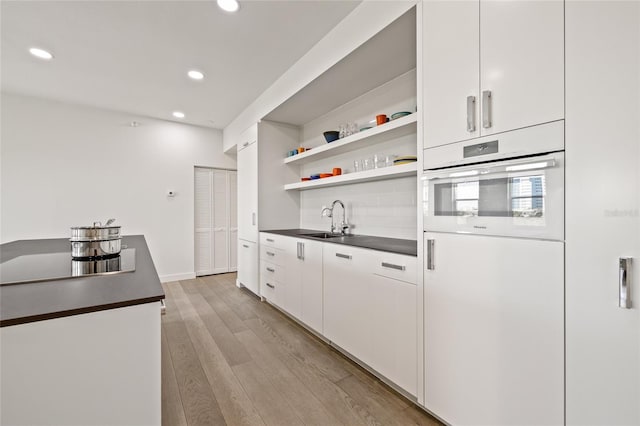 kitchen featuring a sink, dark countertops, oven, recessed lighting, and open shelves