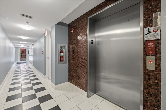 205 5th Ave N Unit 501, Saint Petersburg, FL 33701 - corridor with elevator, brick wall, and baseboards