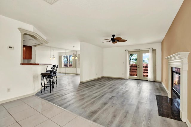 14561 El Paseo Dr, Seminole, FL 33776 - unfurnished living room featuring plenty of natural light, a fireplace with flush hearth, ceiling fan, and wood finished floors