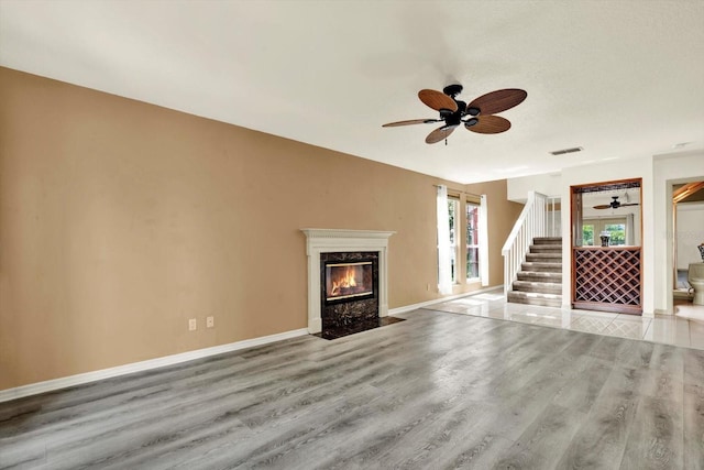 14561 El Paseo Dr, Seminole, FL 33776 - unfurnished living room featuring ceiling fan, wood finished floors, a fireplace, and stairway
