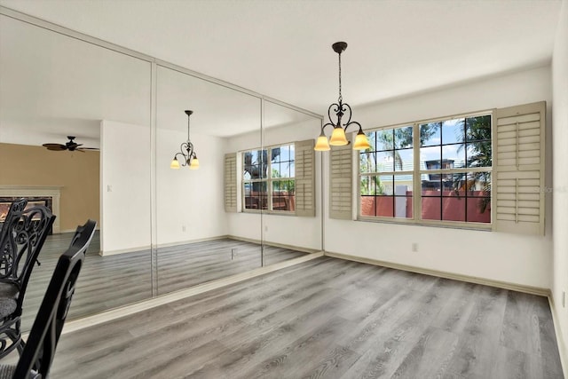 14561 El Paseo Dr, Seminole, FL 33776 - unfurnished dining area featuring a chandelier, wood finished floors, baseboards, and ceiling fan