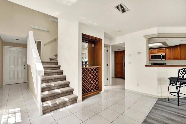 14561 El Paseo Dr, Seminole, FL 33776 - interior space featuring appliances with stainless steel finishes, brown cabinetry, light tile patterned floors, and baseboards
