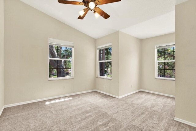 14561 El Paseo Dr, Seminole, FL 33776 - carpeted empty room featuring plenty of natural light, baseboards, a ceiling fan, and vaulted ceiling