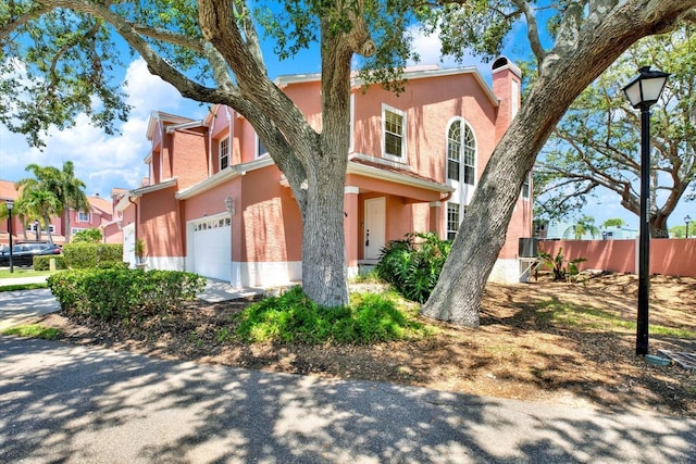 14561 El Paseo Dr, Seminole, FL 33776 - view of front of home featuring a garage, stucco siding, a chimney, and a residential view