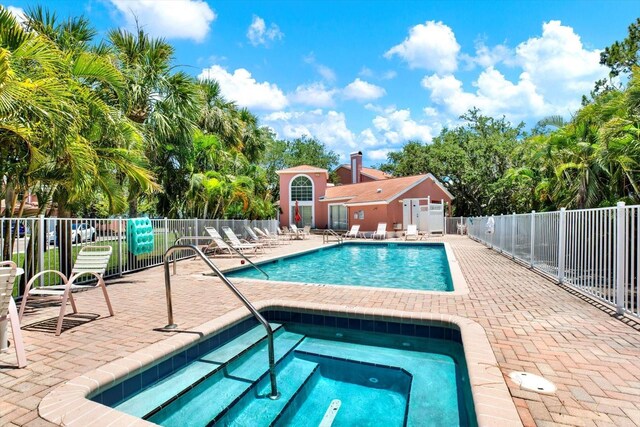 14561 El Paseo Dr, Seminole, FL 33776 - community pool featuring a community hot tub, a patio, and view of scattered trees