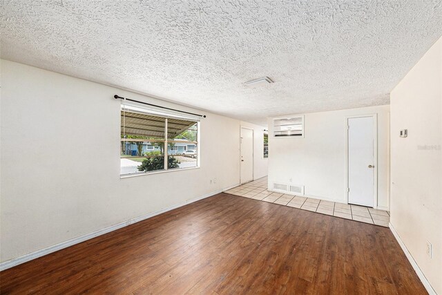 spare room featuring wood-type flooring, baseboards, and a textured ceiling