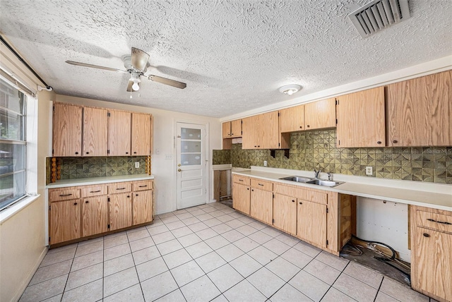 kitchen with a sink, backsplash, a ceiling fan, light countertops, and light tile patterned floors