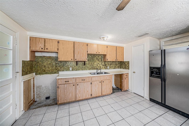 kitchen featuring stainless steel fridge with ice dispenser, a sink, light tile patterned floors, and tasteful backsplash